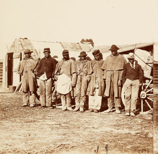 Contrabands wearing military overcoats and kepis.